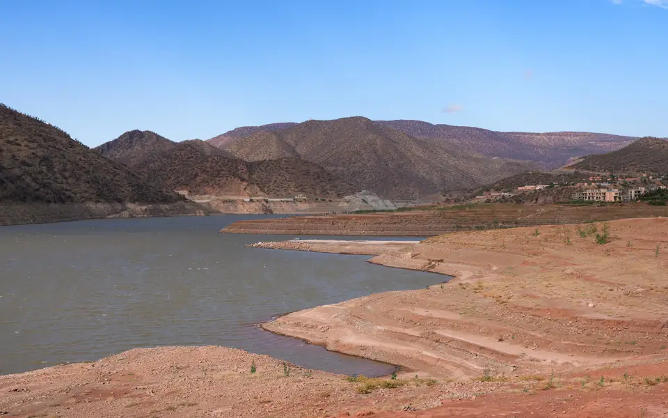 Rives de terre rouge du lac d'Ouirgane avec les montagnes en arrière-plan