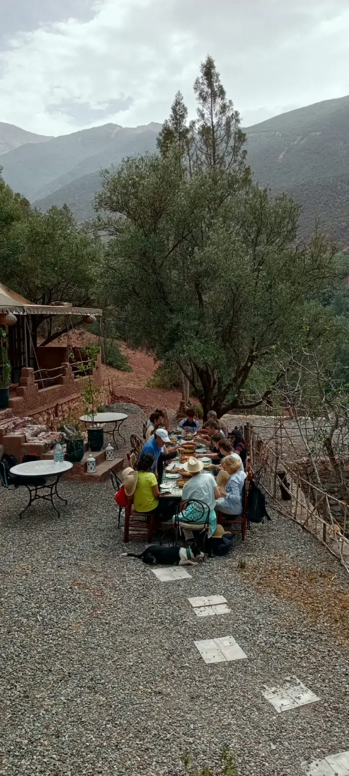 Visiteurs attablés sur une terrasse en gravier dominant les montagnes